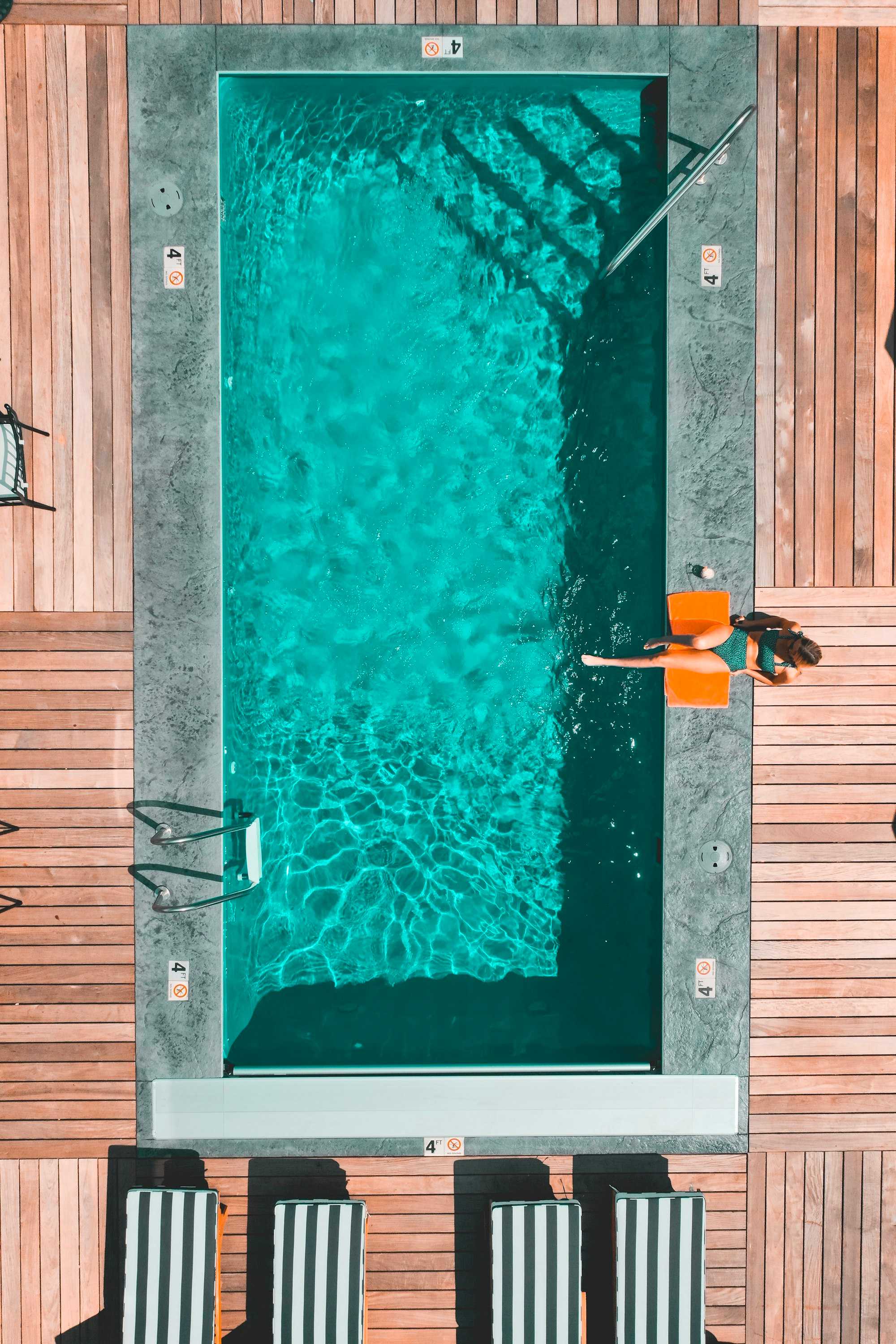 Vue aérienne d’une piscine rectangulaire turquoise entourée d’une terrasse en bois