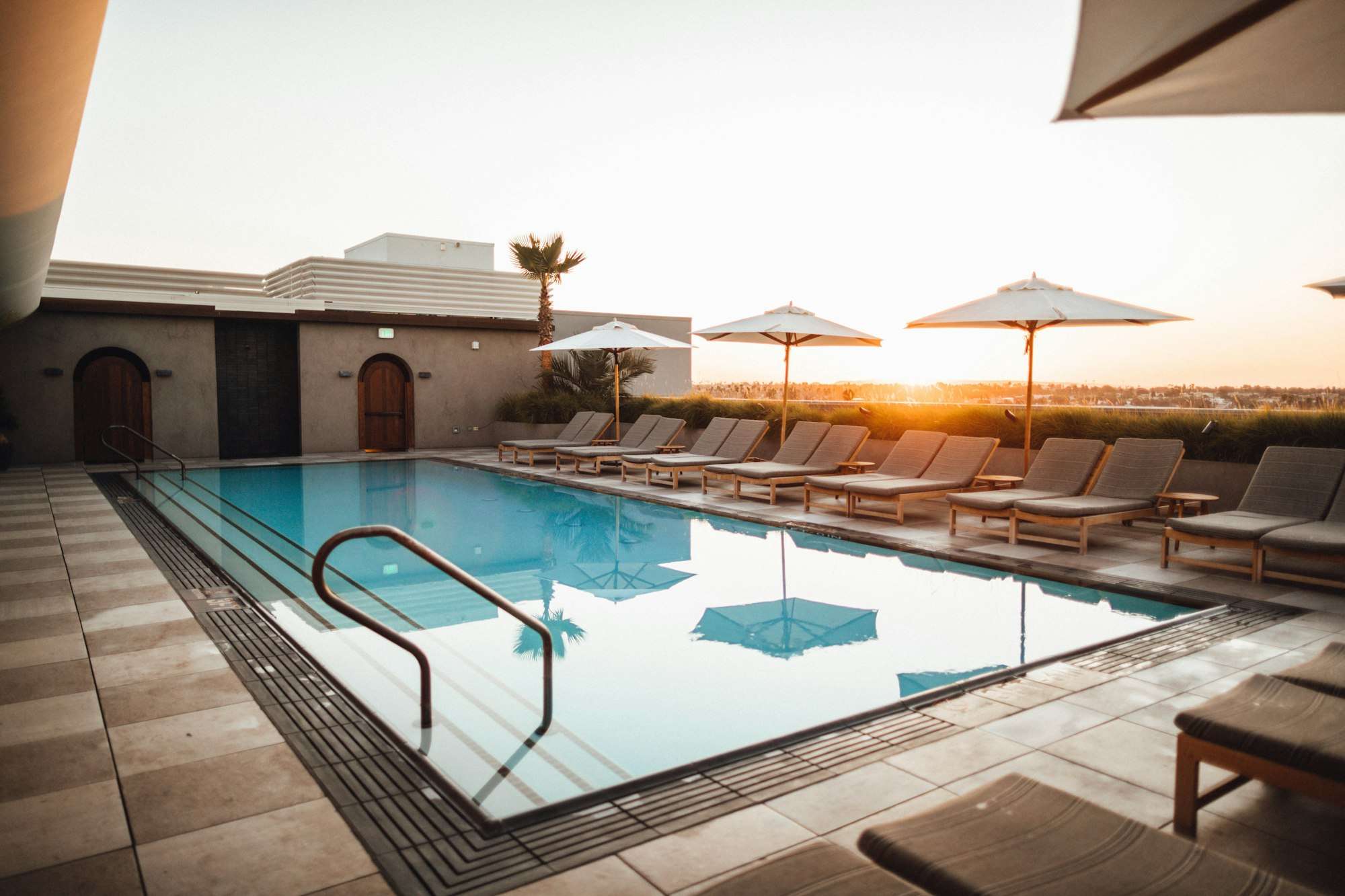 Piscine en couloir sur une terrasse au coucher du soleil, bordée de transats